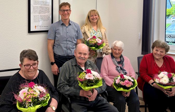 Mitglieder des neuen Heimbeirats und weitere Personen mit Blumensträußen